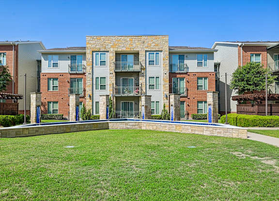 Apartment complex with a grassy front yard.