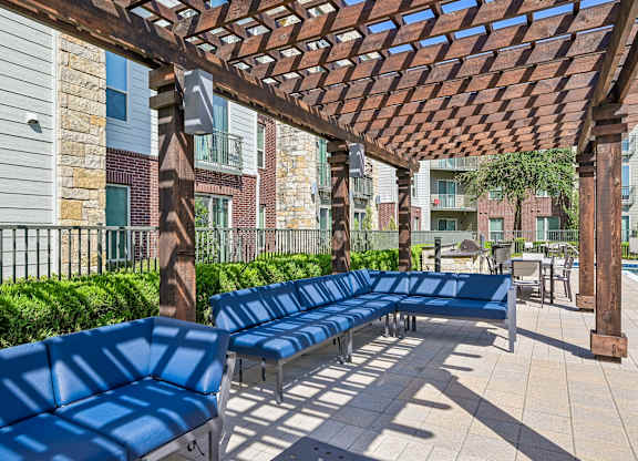 A row of blue benches are lined up under a wooden pergola.