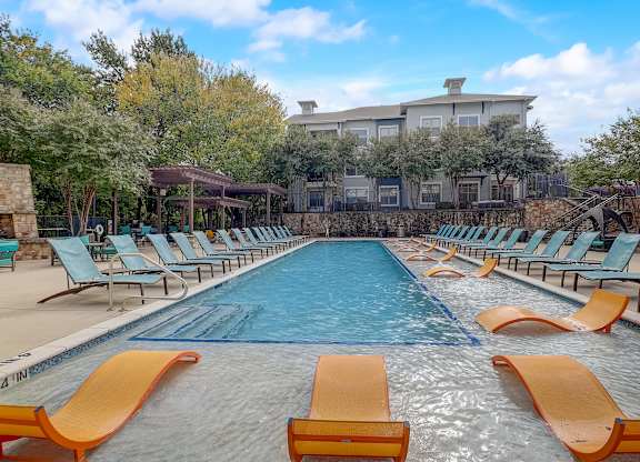 a swimming pool with chairs and a building in the background