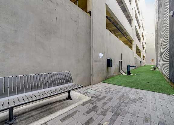 A bench sits on a brick walkway between two buildings.