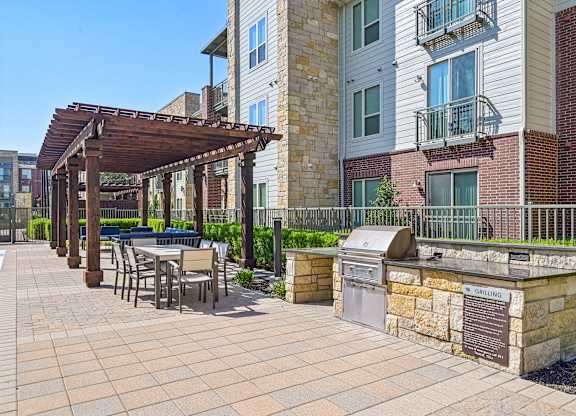 A patio with a table and chairs under a pergola.