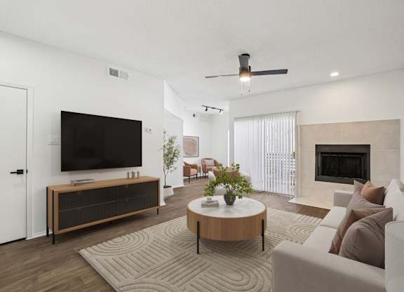 A modern living room with a flat screen TV, a fireplace, and a ceiling fan.