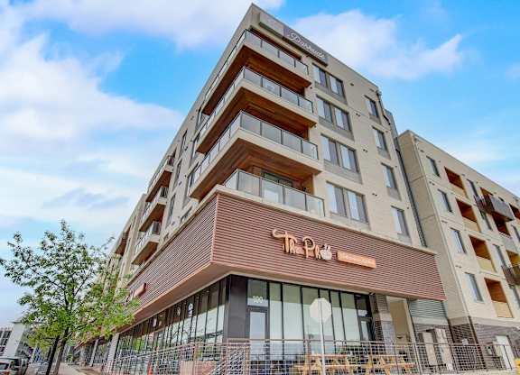 Mixed-use building corner with street-level storefront windows and upper residential balconies.
