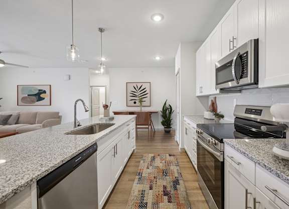 A modern kitchen with white cabinets and granite countertops.