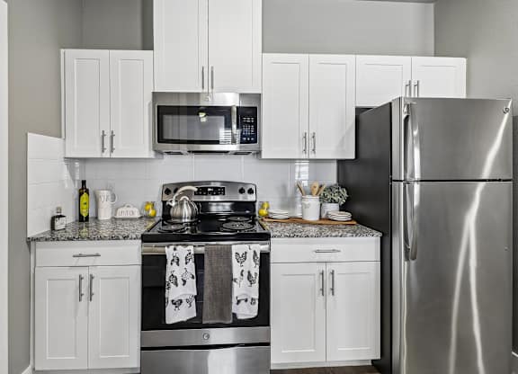 A modern kitchen with a stainless steel refrigerator, microwave, and oven.