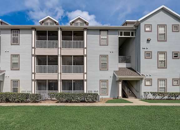 an apartment building with balconies and a grass yard