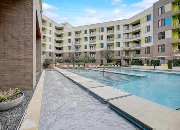 Shallow water feature with fountains beside the main pool and sun deck seating.