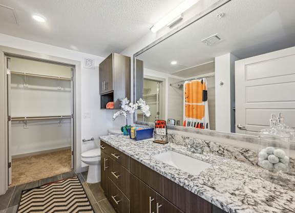 A bathroom with a marble countertop and a striped rug.