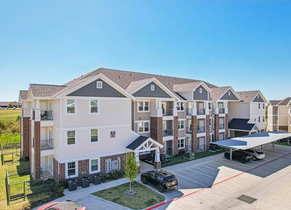 A large apartment complex with a parking lot in front.