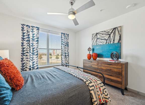 A bedroom with a bed, a dresser, and a painting on the wall.