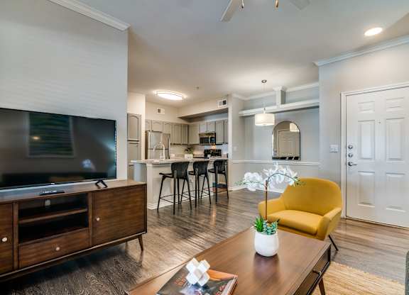 a living room with a tv and a kitchen in the background