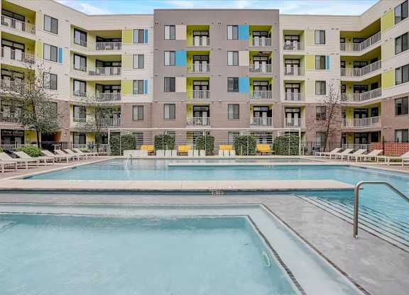 Courtyard swimming pool with shallow ledge and sun loungers surrounded by apartments.