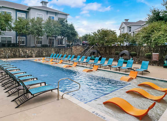 a swimming pool with blue chairs and yellow and orange chairs