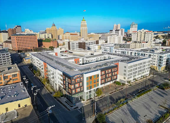 A cityscape with a large building in the foreground and a clear blue sky above.