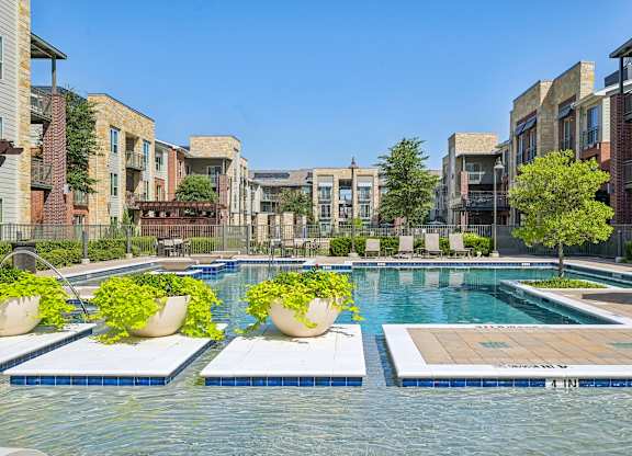 A swimming pool surrounded by buildings and potted plants.