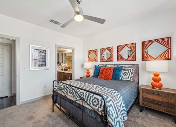 A bedroom with a bed, a dresser, and a ceiling fan.