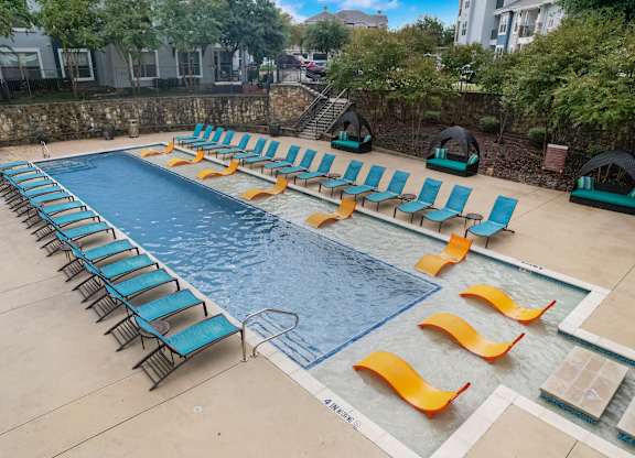 a swimming pool with lounge chairs and chairs around it