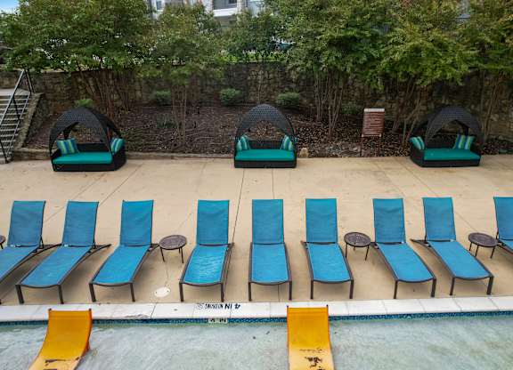 a row of blue and green chairs on the side of a pool