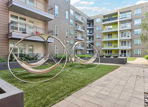 A playground with a swing set in the foreground and apartment buildings in the background.