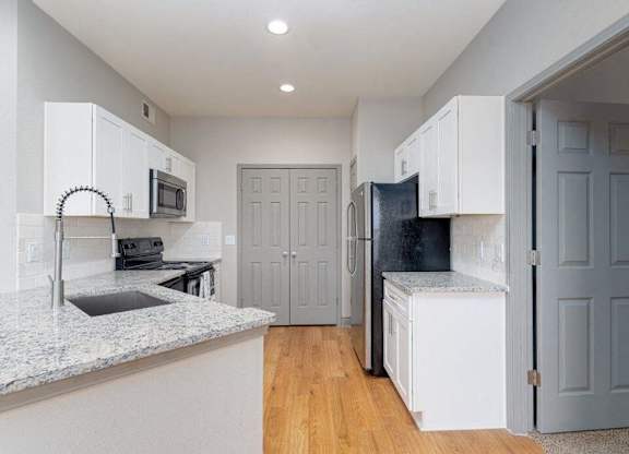 a kitchen with white cabinets and a sink and a refrigerator