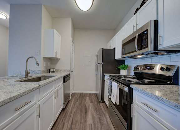 a kitchen with white cabinets and a stove and a sink