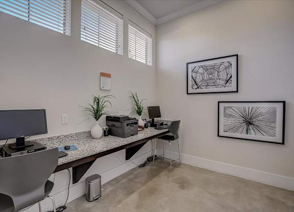 Business center workspace with computers, printer, and framed wall art.