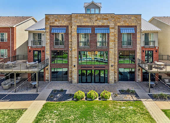A large building with a brick facade and a green lawn in front.