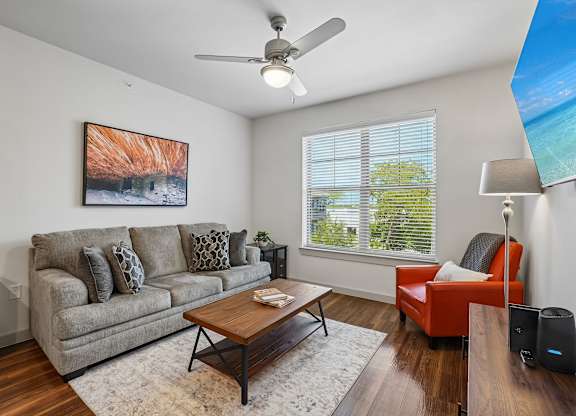 A living room with a grey couch, a red chair, a coffee table, and a painting on the wall.
