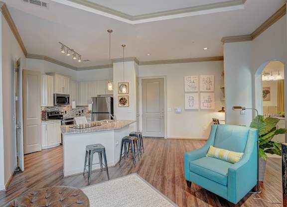 a living room with a kitchen with a bar and a blue chair