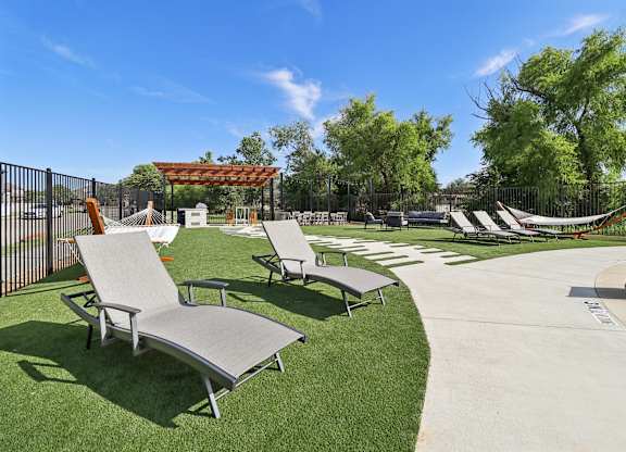 A sunny day at the pool with lounge chairs and a hammock.