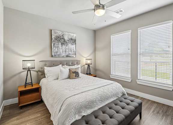 A bedroom with a large bed, a ceiling fan, and two lamps.
