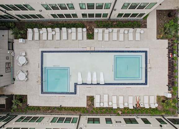 A swimming pool surrounded by white chairs and plants.