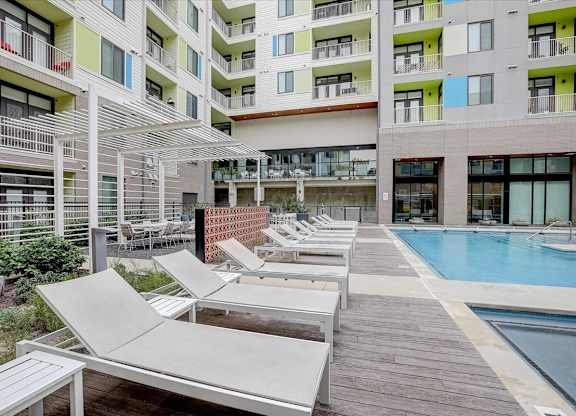 Pool courtyard with pergola seating, loungers, and glass-walled amenity spaces nearby.