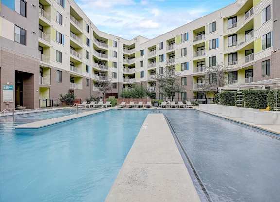 Wide pool and shallow water feature framed by landscaped courtyard and pool loungers.