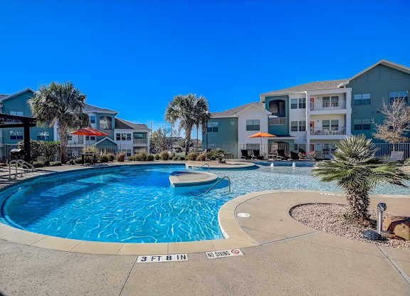 Curved pool in courtyard with palm trees and apartment buildings.