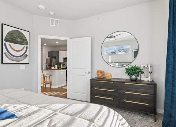 A bedroom with a large bed, a dresser, and a mirror.