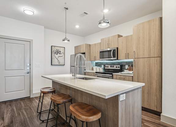 A kitchen with a white countertop and wooden cabinets.