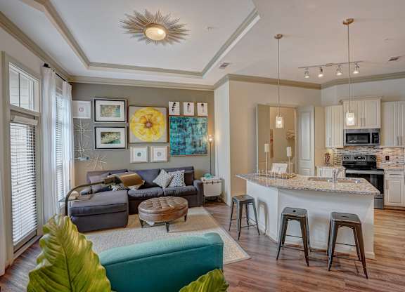 a living room with a kitchen and a bar with stools