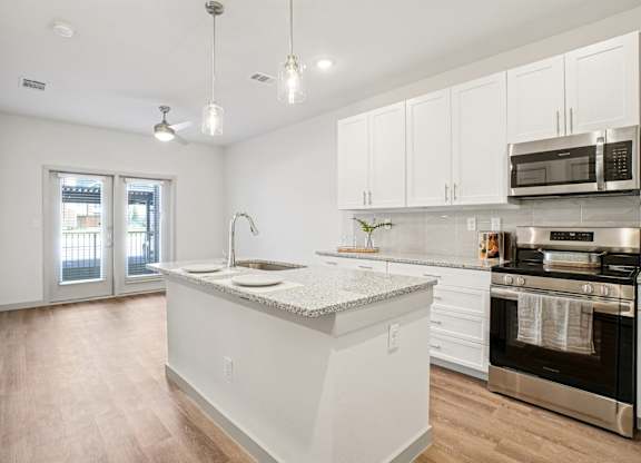 A kitchen with white cabinets and a granite countertop.