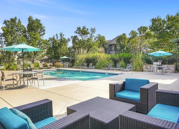 a swimming pool with patio furniture and umbrellas