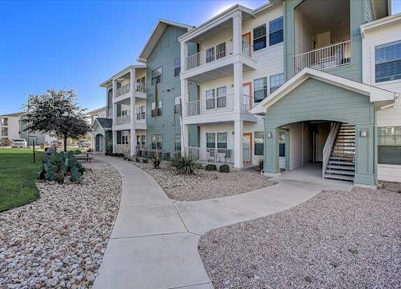 Apartment building exterior with balconies along curved concrete walkway.