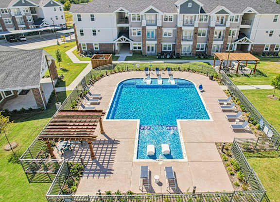 A large swimming pool surrounded by a fence and a building in the background.