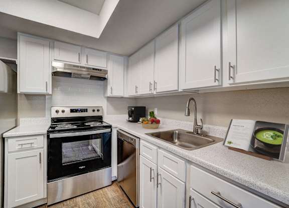 a kitchen with white cabinets and appliances and a sink