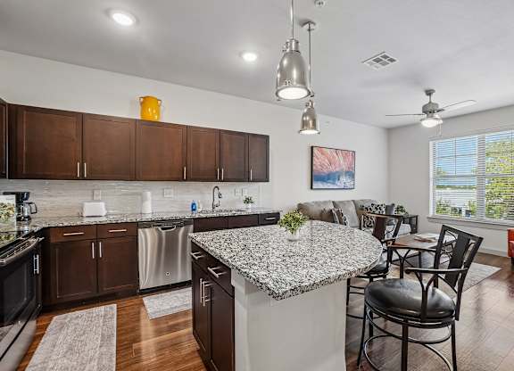 A kitchen with a granite countertop and a dining table with chairs.