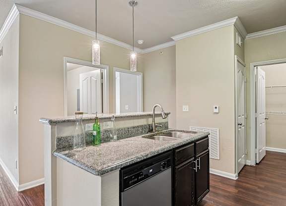 A kitchen with a granite countertop and a green bottle on it.