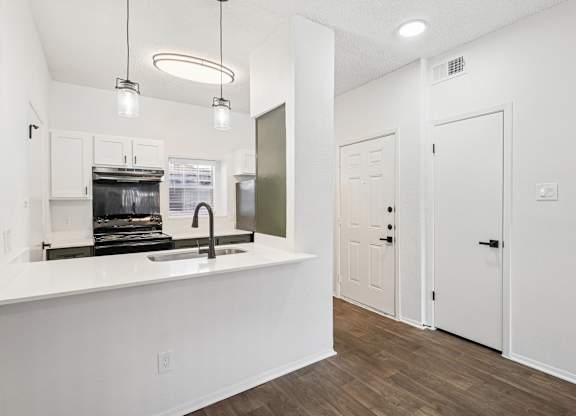 A kitchen with white cabinets and a white countertop with a sink.