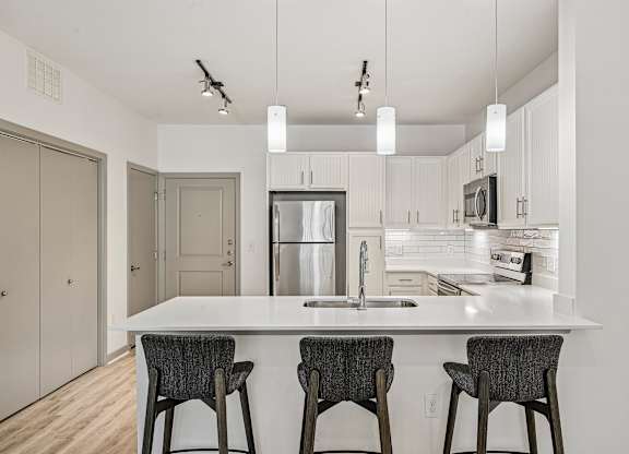 A kitchen with a white countertop and a refrigerator in the middle.