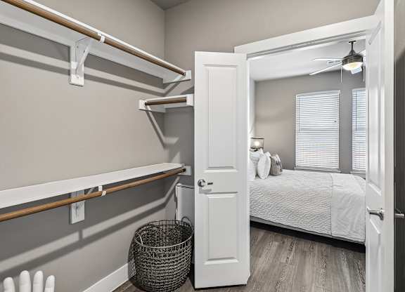 A bedroom with a bed, a window with blinds, and a basket on the floor.