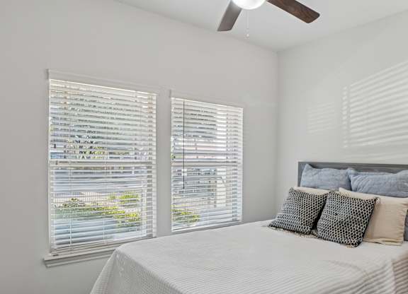 A bedroom with a bed, pillows, and a window with blinds.
