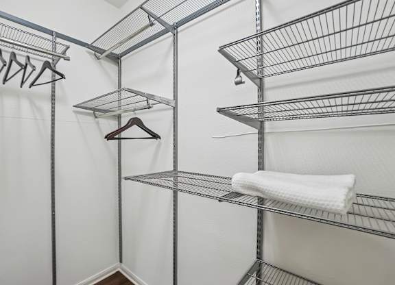 A white closet with a metal shelf and a white towel hanging on it.